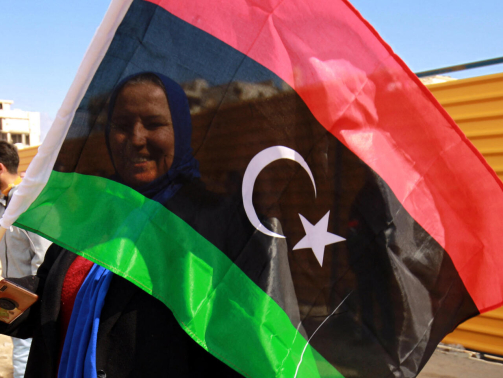 A woman waves a national flag as Libyans mark the 10th anniversary of the 2011 revolution, in the eastern city of Benghazi, on February 17, 2021. - The uprising toppled longtime ruler Moamer Kadhafi, ending a long-lived dictatorship but throwing the country into a decade of violent lawlessness. (Photo by Abdullah DOMA / AFP)